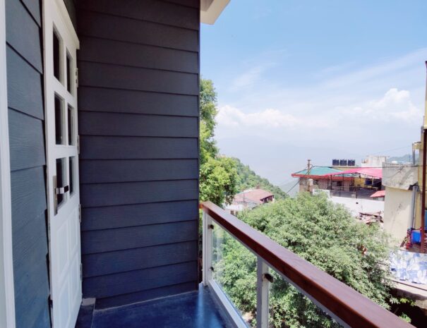 Scenic view from hotel Dwapar room's balcony overlooking lush greenery and distant mountains.