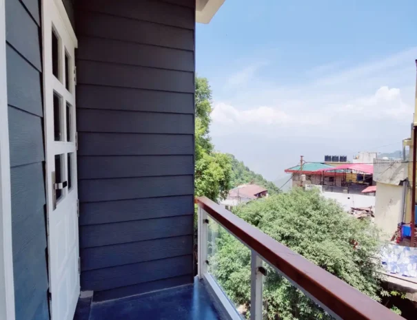 A spacious hotel room with a balcony overlooking majestic mountains.